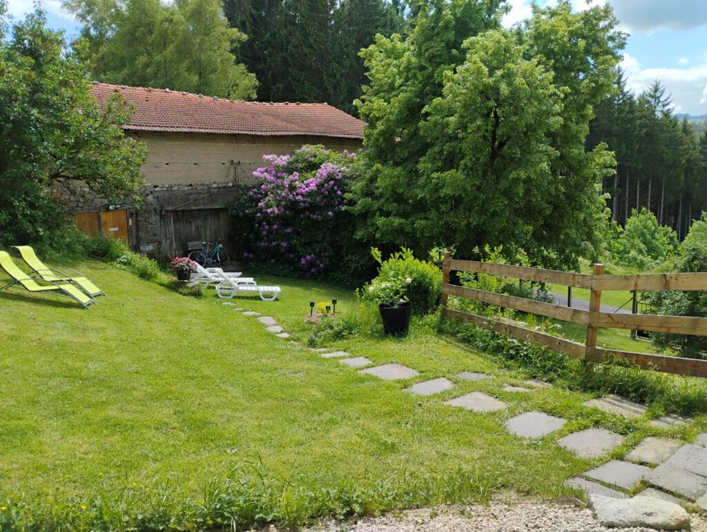 Jardin du gîte du Domaine de la Chouette, avec transats, verdure et vue sur la campagne auvergnate.
