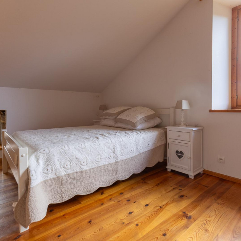 Chambre du Domaine de la Chouette sous les toits, avec lit double, poutres et lumière naturelle.
