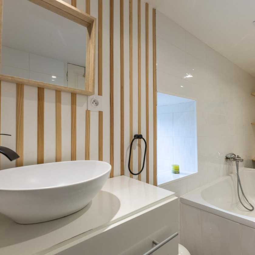 Salle de bain du Domaine de la Chouette avec baignoire, vasque moderne et éléments en bois.