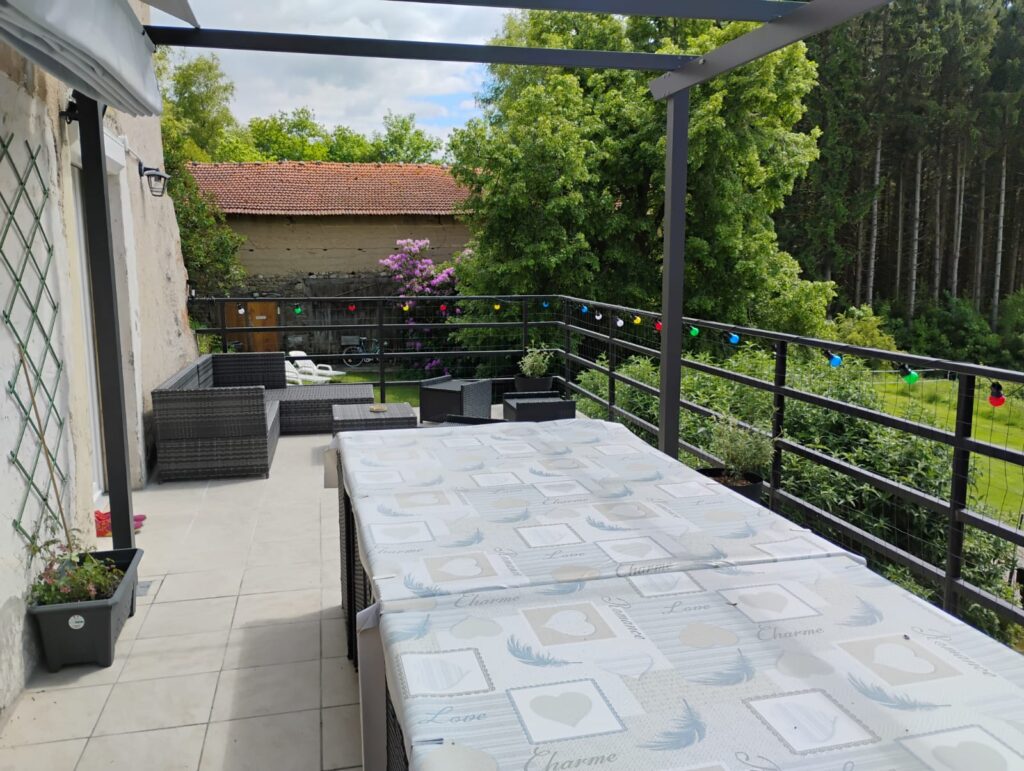 Terrasse du Domaine de la Chouette avec table décorée, salon extérieur et vue sur le jardin.