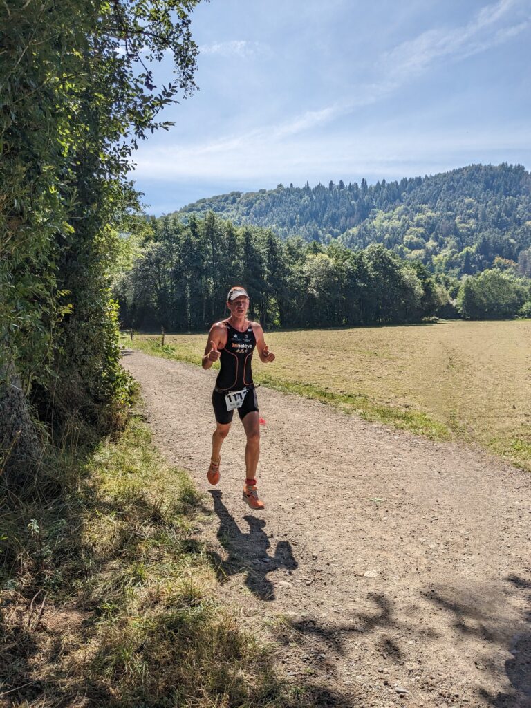 Coureur en tenue de triathlon sur un sentier du Livradois-Forez, entouré de forêt.