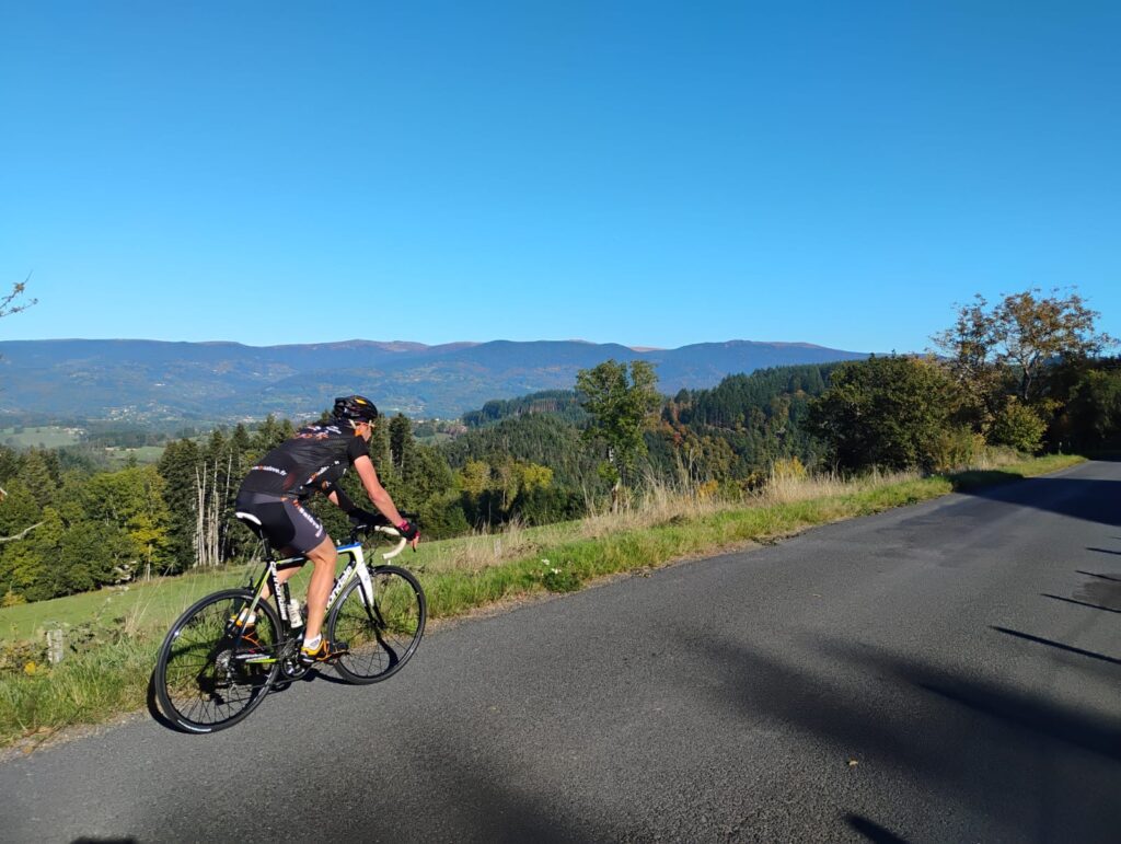 Cycliste s’entraînant sur une route du Livradois-Forez, entourée de forêts et montagnes.