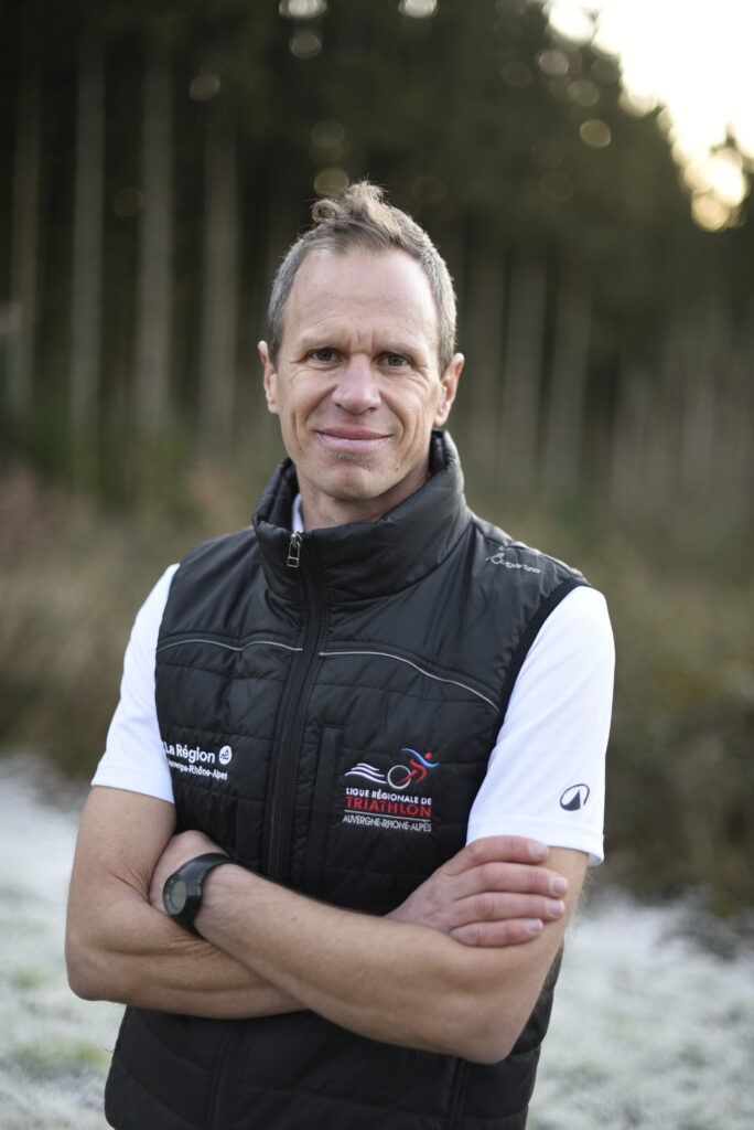 “Portrait d’Ivan, coach de triathlon au Domaine de la Chouette, devant un fond de forêt.